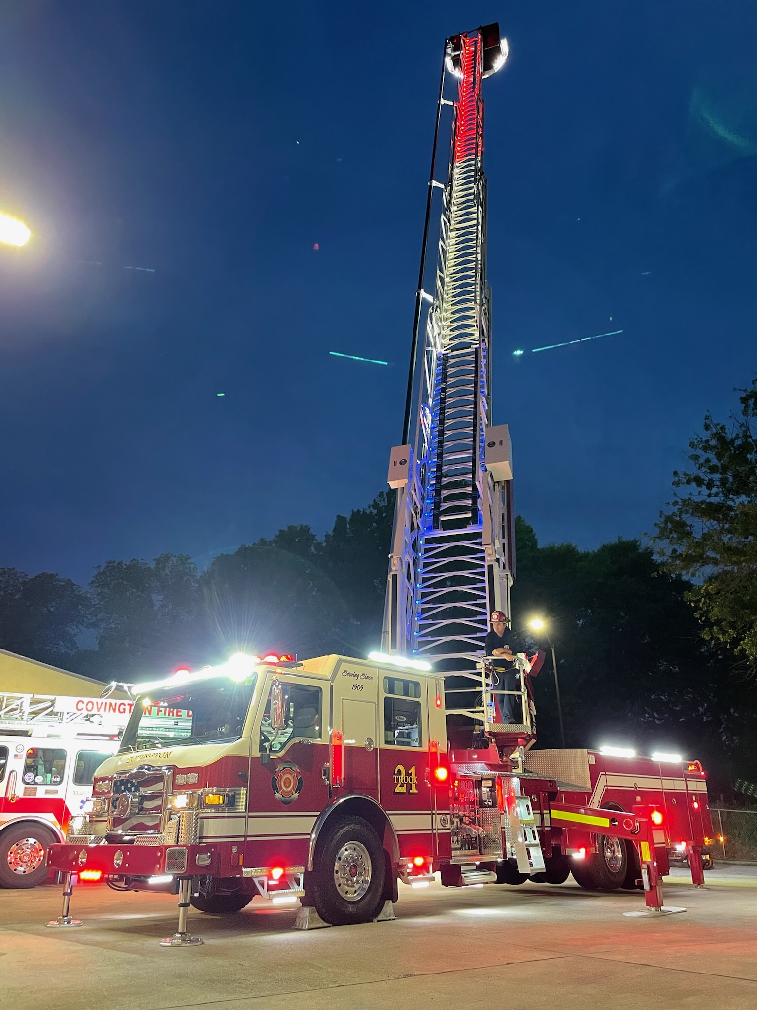 Covington Fire Department ladder truck illuminated at night with its aerial ladder raised high